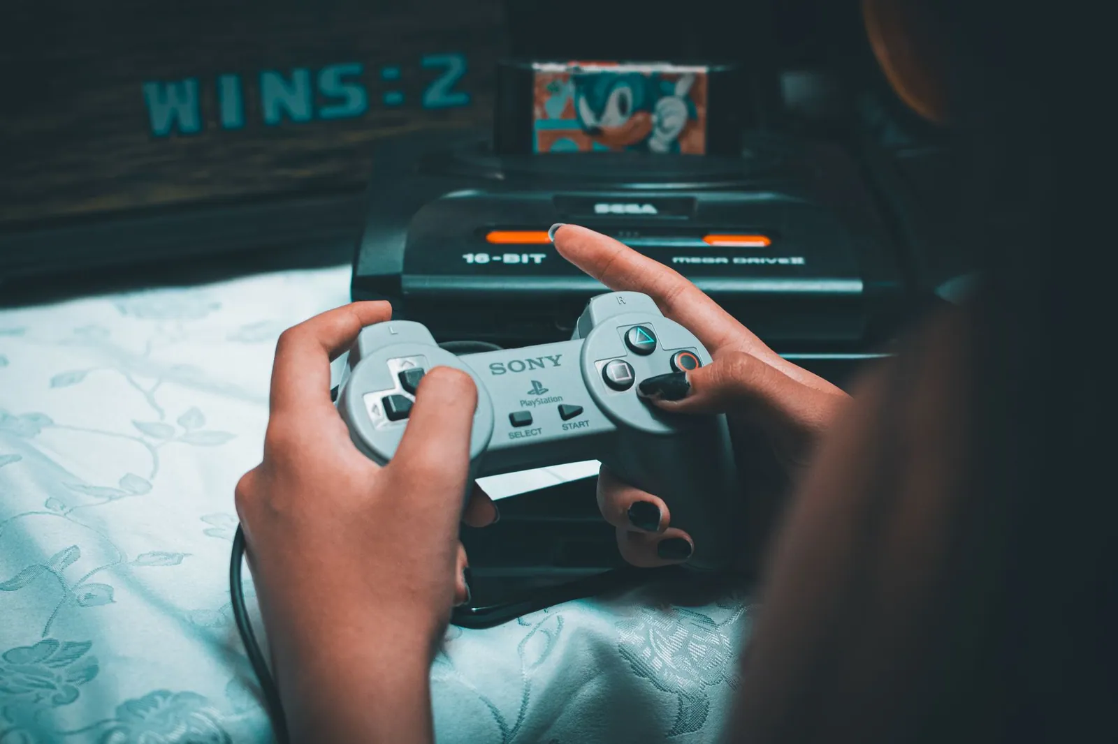Mains tenant une manette sur une console Mega Drive, avec Sonic à l'écran