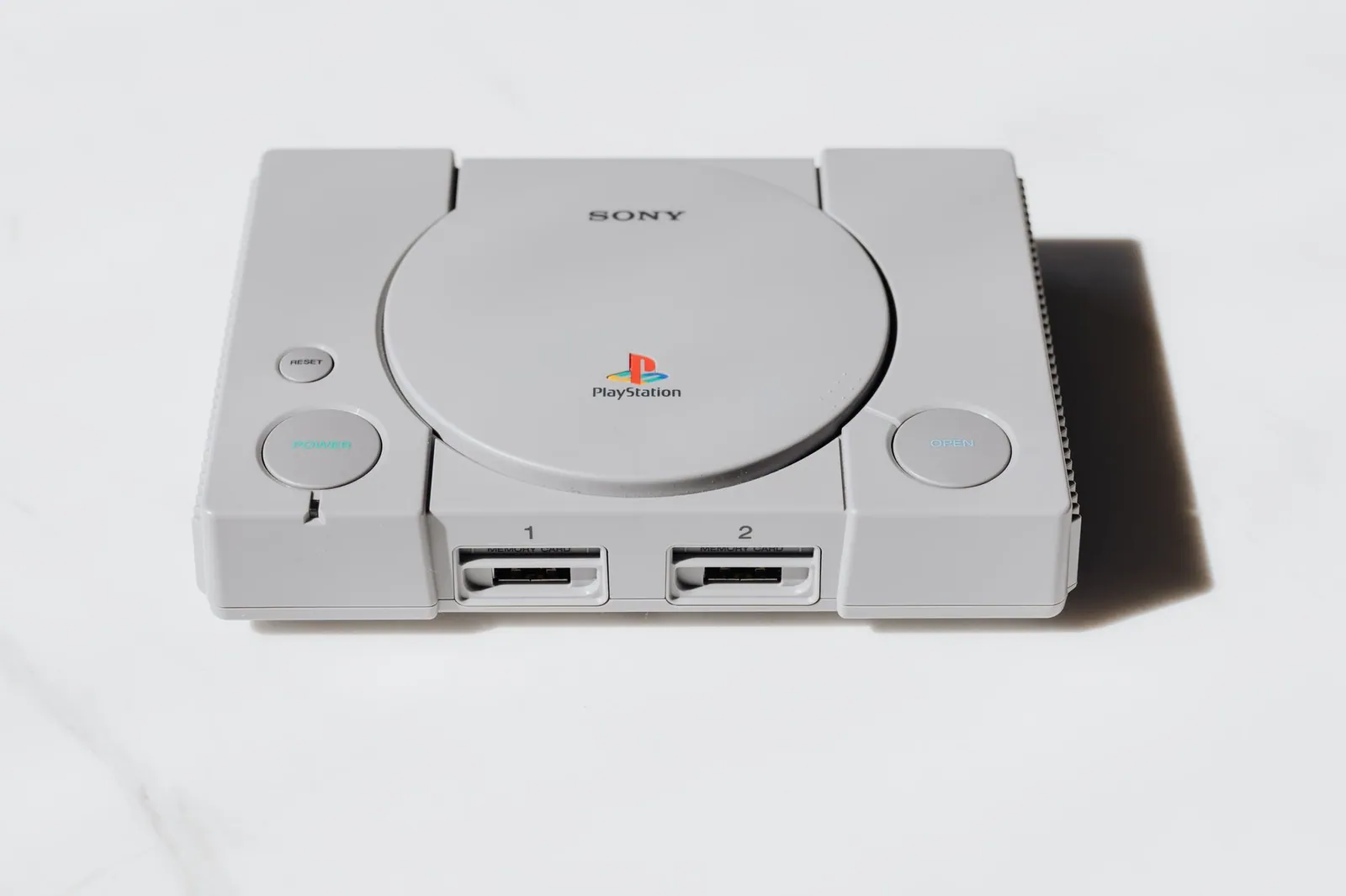 Console PlayStation grise des années 90 sur fond blanc