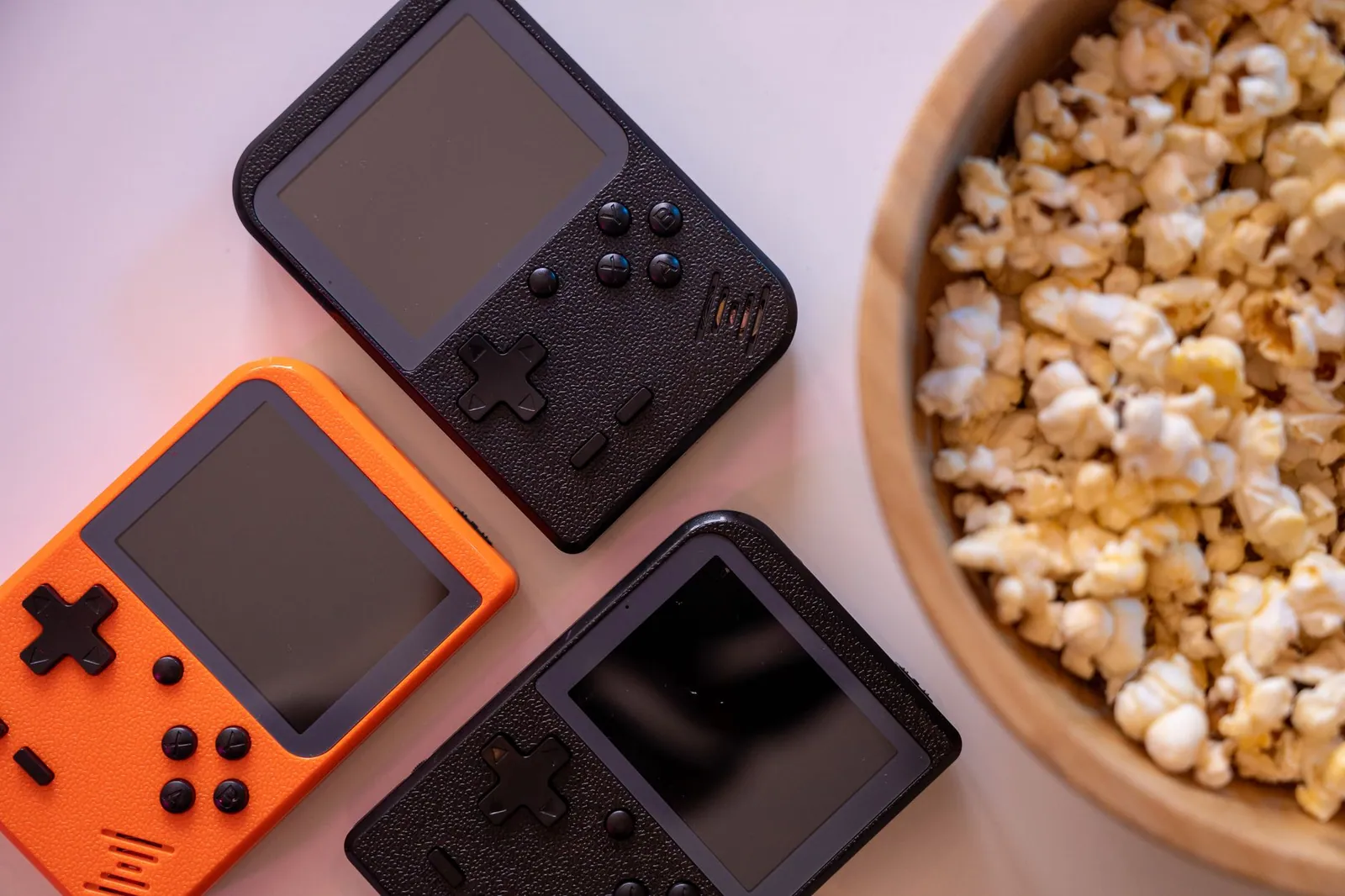 Consoles portables rétro orange et noire à côté d'un bol de pop-corn
